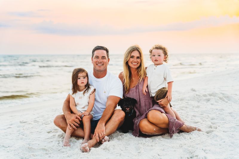 Family of 4 sitting on a beach 30a Florida, sunset and gulf in background