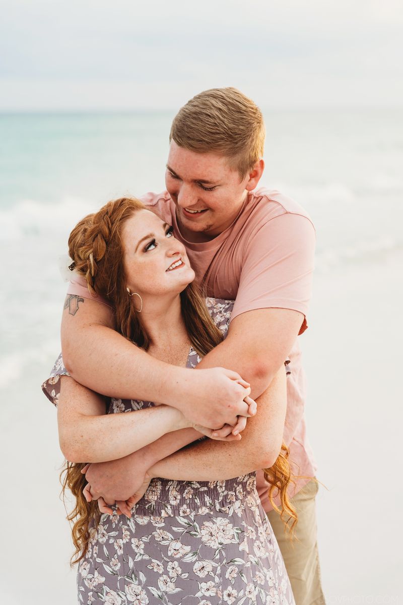 Guy hugging his girlfriend from behind on a beach sunset destin photoshoot