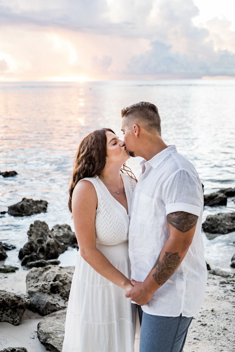 couple kissing on a beach, sunset time with pink clouds