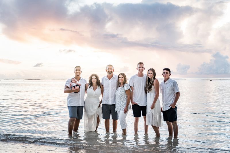 Big family posing for a picture standing in water, sunset time on a beach