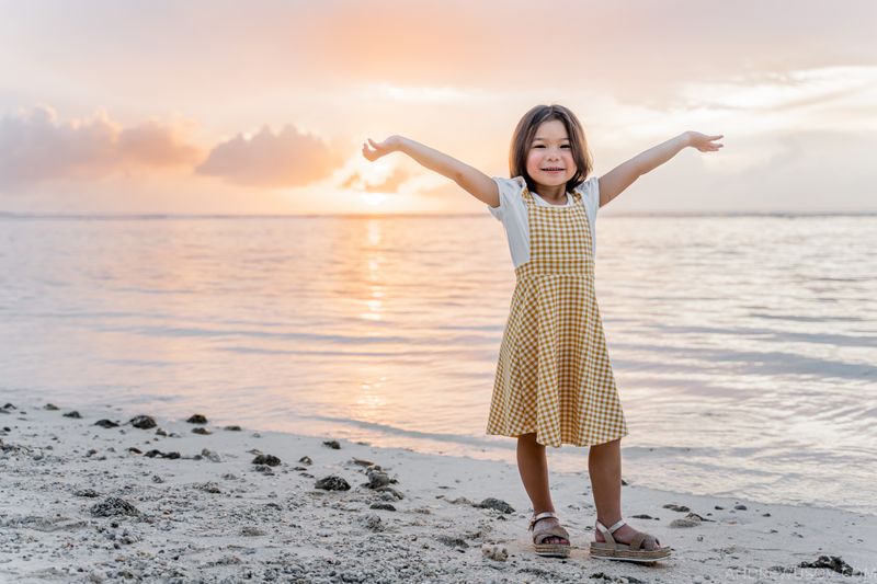 little girl admiring sunset, colorful sky with ocean on the background