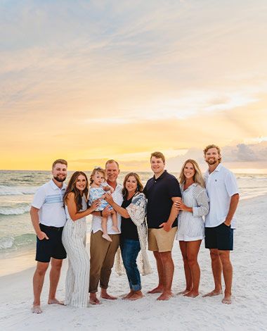 extended family three generations on a beach, sunset sky and gulf in the background