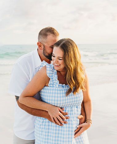 maternity photoshoot with partner, man is hugging pregnant woman from behind, both laughing